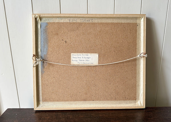 Framed artwork with a label on a wooden surface and white wall background