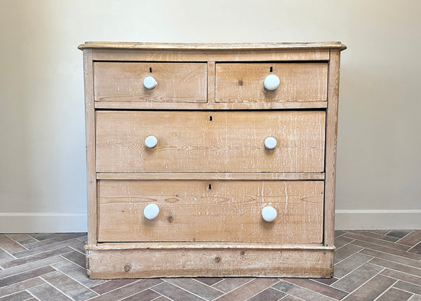 Wooden dresser with white knobs on a tiled floor against a beige wall